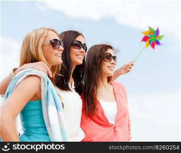 summer holidays, vacation and ecology concept - girls with windmill toy on the beach