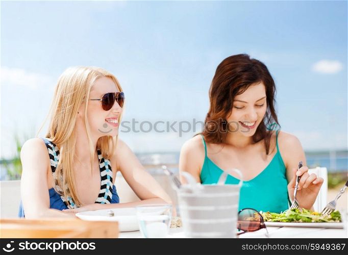 summer holidays, vacation and food concept - girls eating and drinking in cafe on the beach