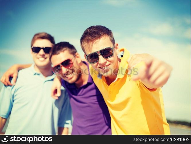 summer, holidays, vacation and happiness concept - group of friends having fun on the beach and pointing at you