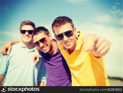 summer, holidays, vacation and happiness concept - group of friends having fun on the beach and pointing at you