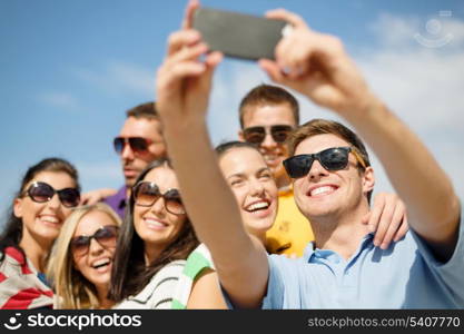 summer, holidays, vacation and happiness concept - group of friends taking picture with smartphone