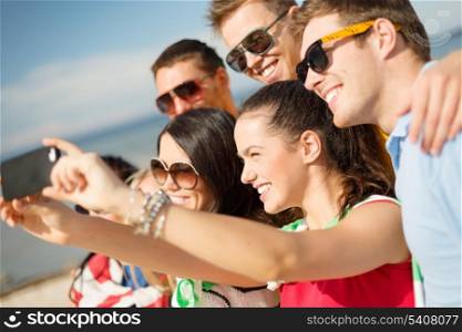 summer, holidays, vacation and happiness concept - group of friends taking picture with smartphone