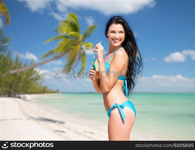 summer holidays, vacation and people concept - happy smiling young woman in bikini with bottle of drink over exotic tropical beach with palm trees background. woman in bikini with bottle of drink on beach