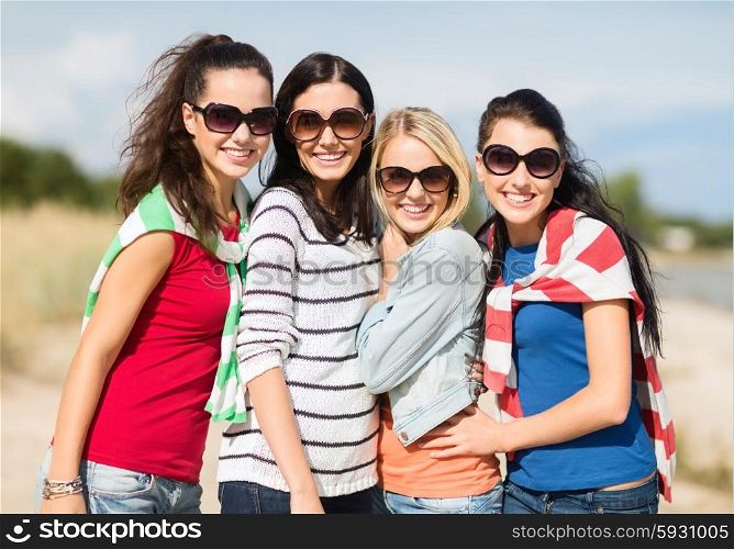 summer holidays, vacation and people concept - happy teenage girls in sunglasses or young women having fun on beach