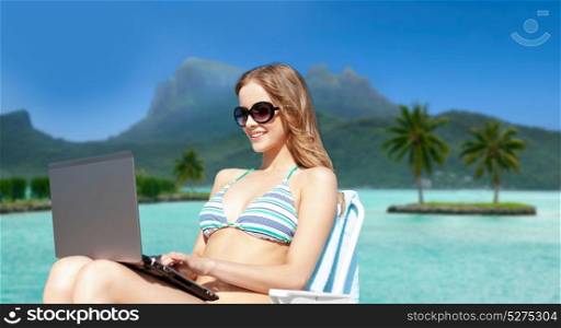 summer holidays, vacation and technology concept - happy young woman in shades with laptop computer over bora bora island beach background. woman in shades with laptop on bora bora beach