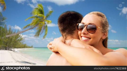 summer holidays, vacation and travel concept - happy couple hugging over tropical beach background in french polynesia. happy couple hugging on summer beach