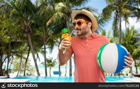 summer holidays, vacation and travel concept - happy man in sunglasses and straw hat with orange juice cocktail and inflatable beach ball on tropical beach background in french polynesia. happy man in straw hat with juice on beach