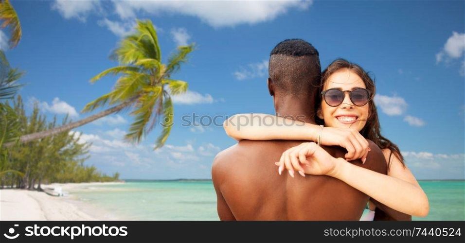 summer holidays, vacation and travel concept - happy mixed race couple hugging over tropical beach background in french polynesia. happy mixed race couple hugging on summer beach