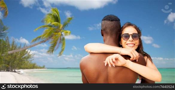 summer holidays, vacation and travel concept - happy mixed race couple hugging over tropical beach background in french polynesia. happy mixed race couple hugging on summer beach