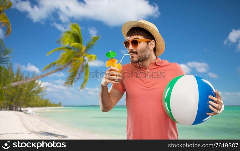 summer holidays, vacation and travel concept - happy young man in sunglasses and straw hat with orange juice cocktail and inflatable beach ball over tropical beach background in french polynesia. happy man in straw hat with juice on beach