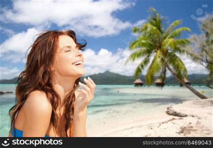 summer holidays, vacation and travel concept - happy young woman enjoying sun over exotic tropical beach with bungalow sheds background. happy woman enjoying sun on tropical beach