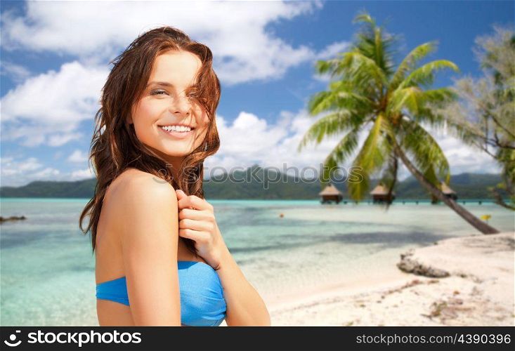 summer holidays, vacation and travel concept - happy young woman posing in bikini swimsuit over exotic tropical beach with bungalow sheds background. happy woman in bikini swimsuit on tropical beach. happy woman in bikini swimsuit on tropical beach