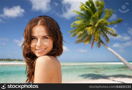 summer holidays, vacation and travel concept - happy young woman posing in bikini swimsuit over exotic tropical beach with palm tree background. happy woman in bikini swimsuit on tropical beach