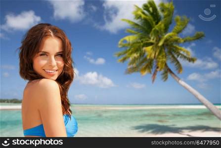 summer holidays, vacation and travel concept - happy young woman posing in bikini swimsuit over exotic tropical beach with palm tree background in french polynesia. happy woman in bikini swimsuit on tropical beach. happy woman in bikini swimsuit on tropical beach