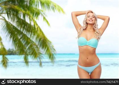 summer holidays, vacation and travel concept - young woman posing in bikini over tropical beach background in french polynesia. young woman posing in bikini on beach