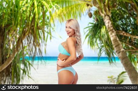 summer holidays, vacation and travel concept - young woman posing in bikini over tropical beach background in french polynesia. young woman posing in bikini on beach