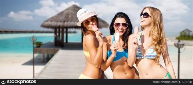 summer holidays, vacation, food, travel and people concept - group of smiling young women eating ice cream over exotic tropical beach with bungalow shed background