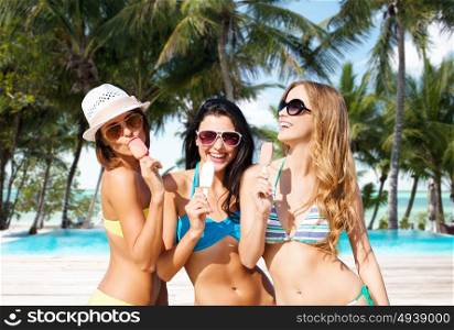 summer holidays, vacation, food, travel and people concept - group of smiling young women eating ice cream over exotic tropical beach with palm trees and pool background. group of smiling women eating ice cream on beach