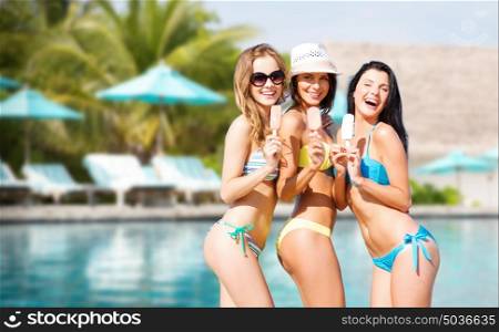 summer holidays, vacation, food, travel and people concept - group of smiling young women eating ice cream over exotic beach with palm trees and pool background. group of smiling women eating ice cream on beach