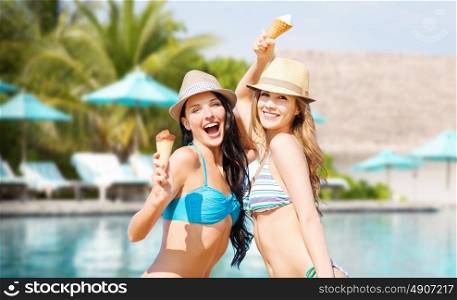 summer holidays, vacation, food, travel and people concept - smiling young women eating ice cream over swimming pool background. smiling women eating ice cream over swimming pool