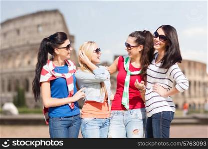 summer, holidays, vacation, friendship and people concept - happy teenage girls or young women in sunglasses talking and laughing over coliseum background