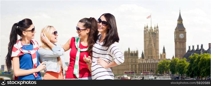 summer, holidays, vacation, friendship and people concept - happy teenage girls or young women in sunglasses talking and laughing over houses of parliament in london background