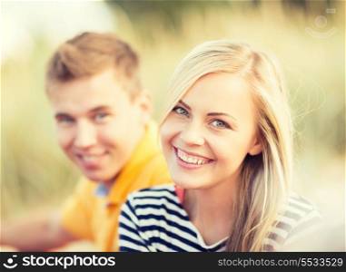 summer, holidays, vacation, happy people and dating concept - couple or friends sitting at the sea side