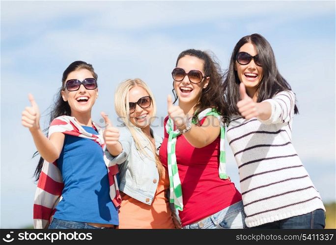 summer, holidays, vacation, happy people concept - beautiful teenage girls or young women showing thumbs up
