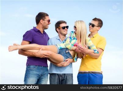 summer, holidays, vacation, happy people concept - group of friends having fun and carrying girl on hands at beach
