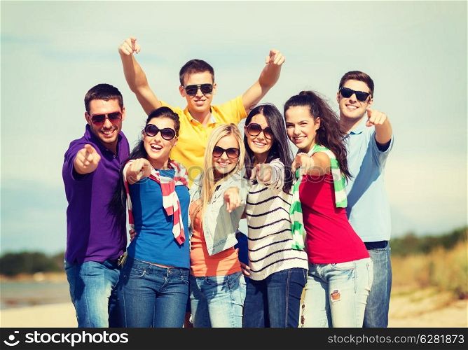 summer, holidays, vacation, happy people concept - group of friends having fun on the beach and pointing at you