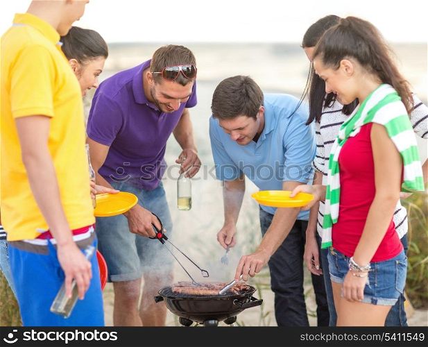 summer, holidays, vacation, happy people concept - group of friends having picnic and making barbecue on the beach
