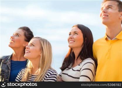 summer, holidays, vacation, happy people concept - group of friends looking up on the beach