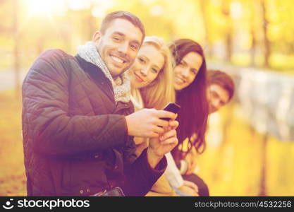 summer, holidays, vacation, happy people concept - group of friends or couples with smartphone having fun in autumn park