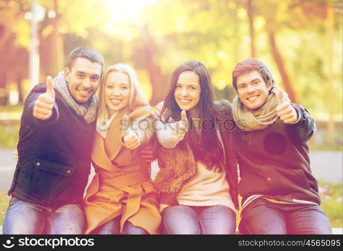 summer, holidays, vacation, happy people concept - group of friends or couples having fun and showing thumbs up in autumn park