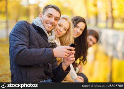 summer, holidays, vacation, happy people concept - group of friends or couples with smartphone having fun in autumn park