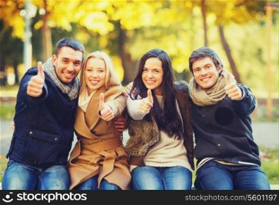summer, holidays, vacation, happy people concept - group of friends or couples having fun and showing thumbs up in autumn park