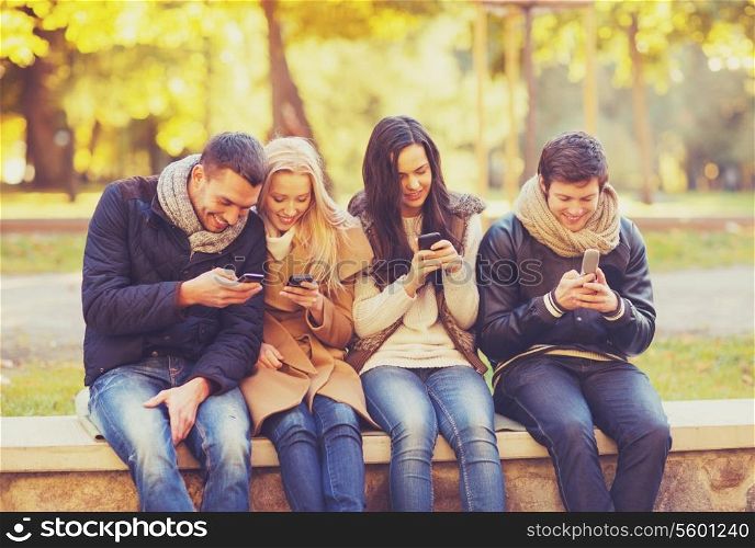 summer, holidays, vacation, happy people concept - group of friends or couples with smartphones having fun in autumn park