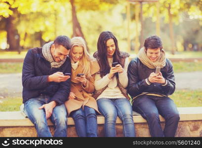 summer, holidays, vacation, happy people concept - group of friends or couples with smartphones having fun in autumn park