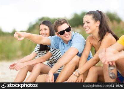 summer, holidays, vacation, happy people concept - group of friends pointing somewhere on the beach