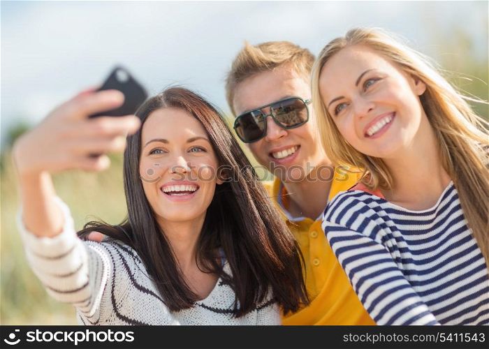summer, holidays, vacation, happy people concept - group of friends taking photo picture with smartphone