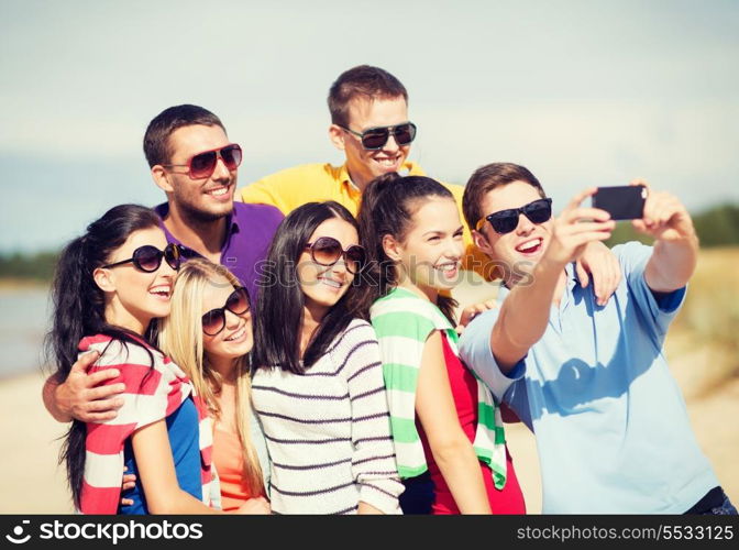 summer, holidays, vacation, happy people concept - group of friends taking picture with smartphone