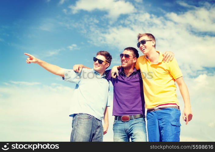 summer, holidays, vacation, happy people concept - group of male friends walking on the beach pointing finger somewhere