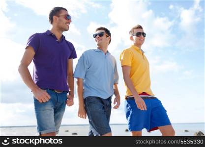 summer, holidays, vacation, happy people concept - group of male friends walking on the beach