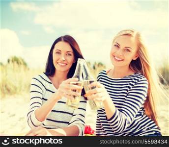 summer, holidays, vacation, happy people concept - smiling girlfriends with bottles of beer or non-alcoholic drinks on the beach