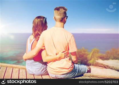 summer holidays, vacation, love and people concept - happy teenage couple sitting on berth over exotic seychelles beach background. happy teenage couple sitting on river berth