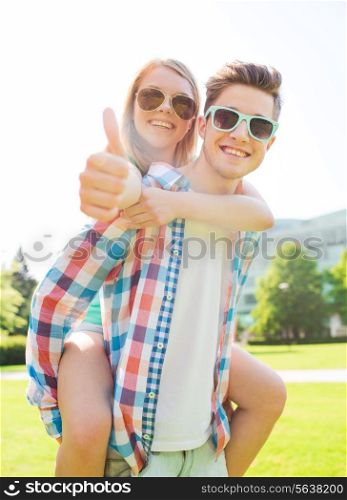 summer holidays, vacation, love, gesture and friendship concept - smiling couple having fun and showing thumbs up in park