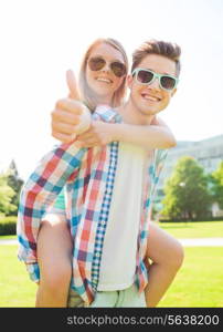 summer holidays, vacation, love, gesture and friendship concept - smiling couple having fun and showing thumbs up in park