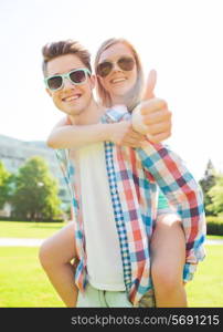 summer holidays, vacation, love, gesture and friendship concept - smiling teen couple in sunglasses having fun and showing thumbs up in park