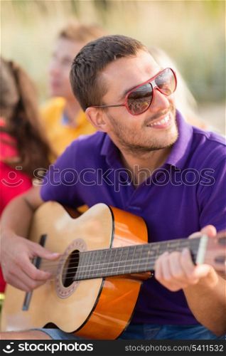 summer, holidays, vacation, music, happy people concept - group of friends with guitar having fun on the beach
