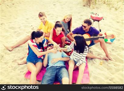 summer holidays, vacation, music, happy people concept - group of friends with guitar having fun on the beach